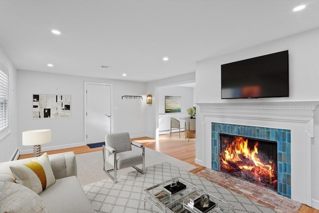 living area featuring light wood finished floors, recessed lighting, and a fireplace