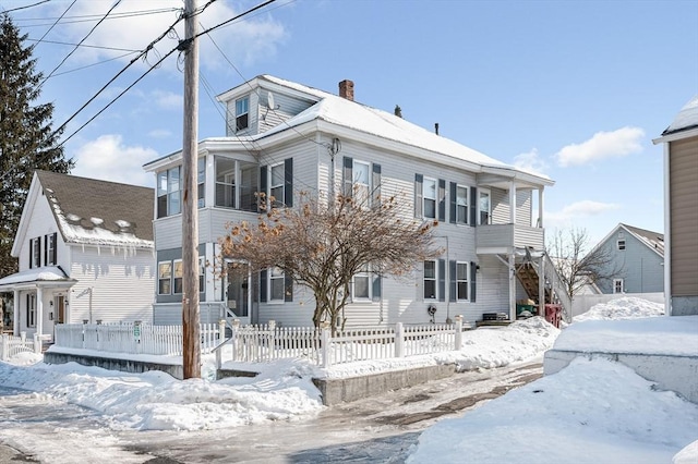 view of front of home featuring stairs, a fenced front yard, and a chimney