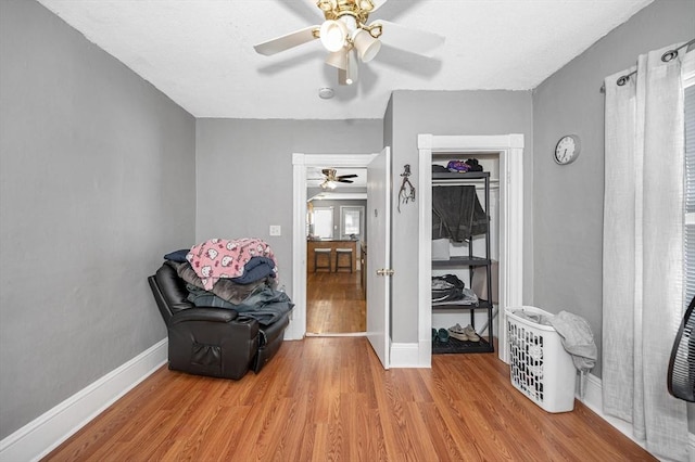 living area featuring light wood-style flooring, baseboards, and ceiling fan