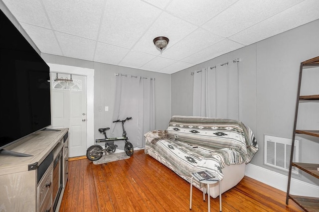 bedroom featuring a paneled ceiling, wood finished floors, and visible vents