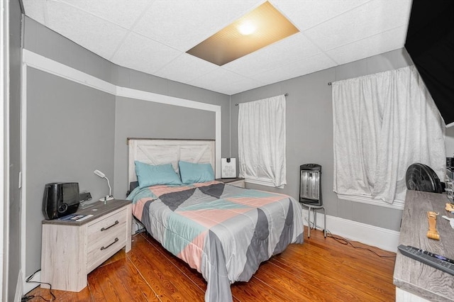 bedroom featuring wood finished floors, a paneled ceiling, and baseboards