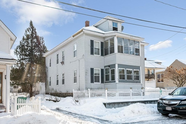 view of front of house featuring a sunroom, fence, and a chimney