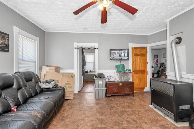 living room with a wainscoted wall, ornamental molding, a ceiling fan, and heating unit