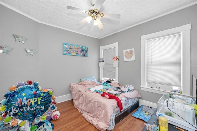 bedroom featuring crown molding, wood finished floors, a ceiling fan, and baseboards