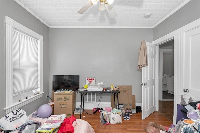 bedroom with a ceiling fan, crown molding, baseboards, and wood finished floors