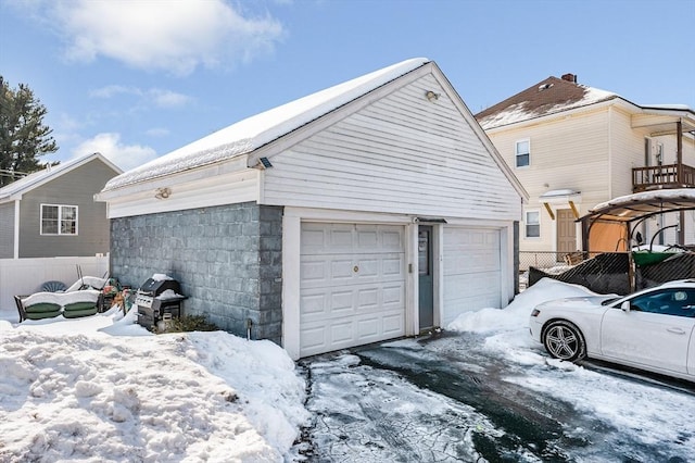 snow covered garage with fence