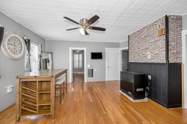 interior space with a wainscoted wall, ceiling fan, visible vents, and wood finished floors