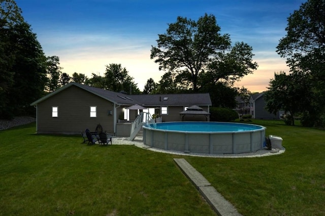 7 Luan Cir, Chelmsford, MA 01824 - back of house at dusk with a lawn and an outdoor pool