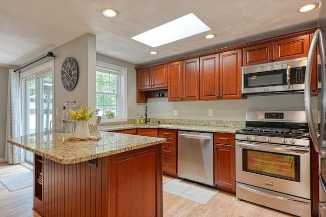7 Luan Cir, Chelmsford, MA 01824 - kitchen featuring stainless steel appliances, a skylight, open shelves, light wood-style floors, and a peninsula