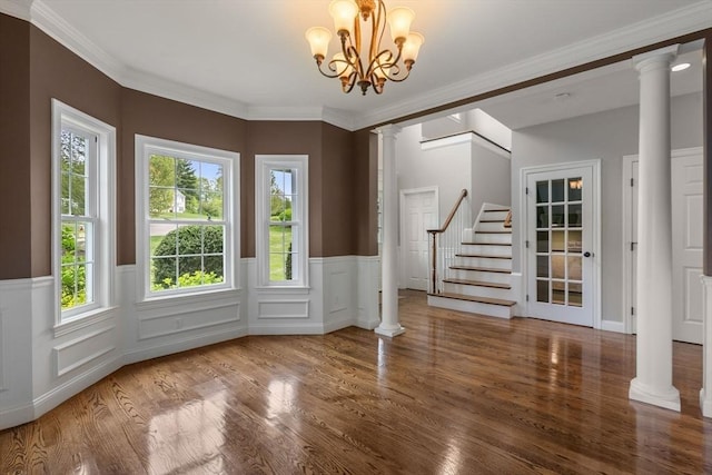 23 Crimson Dr, Shrewsbury, MA 01545 - empty room featuring decorative columns, stairs, wood finished floors, a wainscoted wall, and ornamental molding