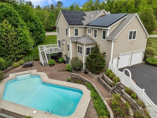 23 Crimson Dr, Shrewsbury, MA 01545 - back of house with stairway, a garage, solar panels, a wooden deck, and a fenced backyard