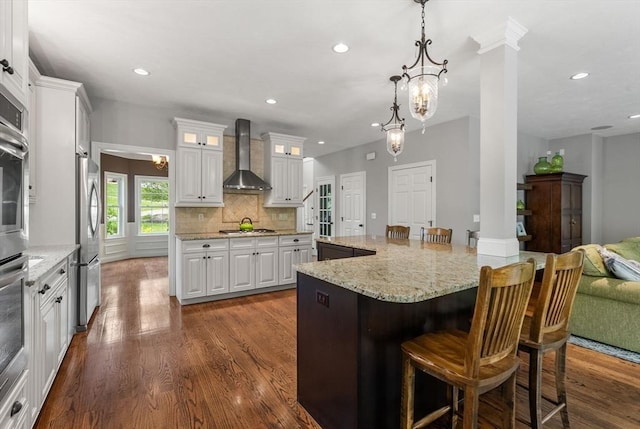 23 Crimson Dr, Shrewsbury, MA 01545 - kitchen with wall chimney exhaust hood, stainless steel appliances, white cabinetry, a kitchen bar, and glass insert cabinets
