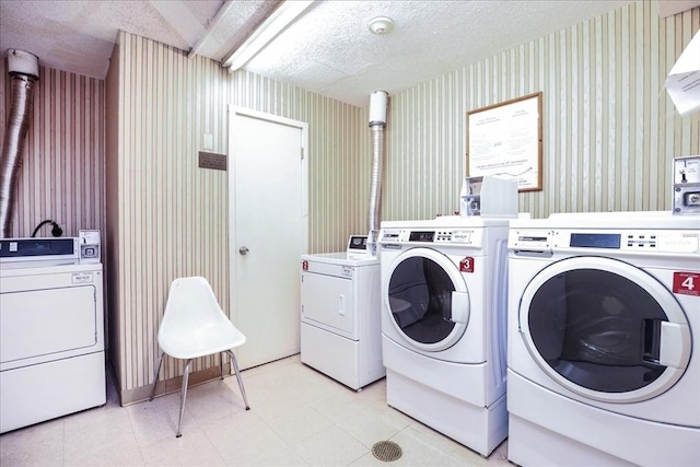 shared laundry room featuring independent washer and dryer, wallpapered walls, and a textured ceiling