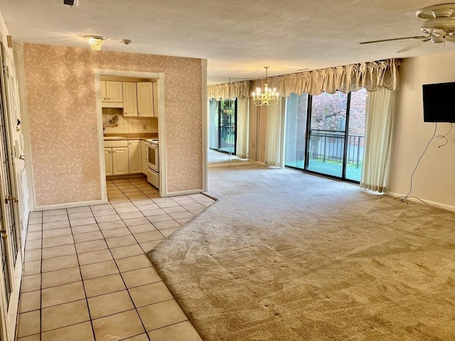 unfurnished living room featuring a chandelier, a ceiling fan, baseboards, light tile patterned flooring, and wallpapered walls