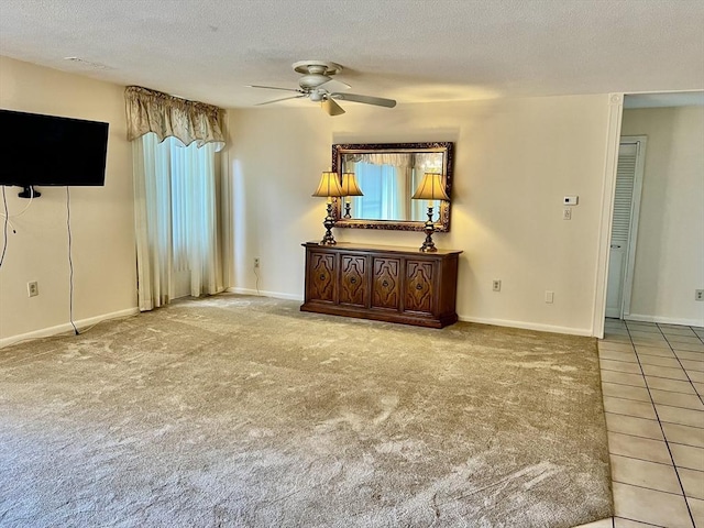 tiled spare room featuring ceiling fan, a textured ceiling, baseboards, and carpet flooring