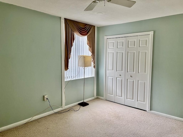 unfurnished bedroom with carpet flooring, baseboards, a ceiling fan, and a closet