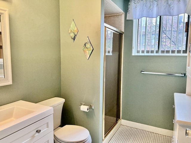 bathroom with a shower stall, toilet, vanity, tile patterned floors, and baseboards