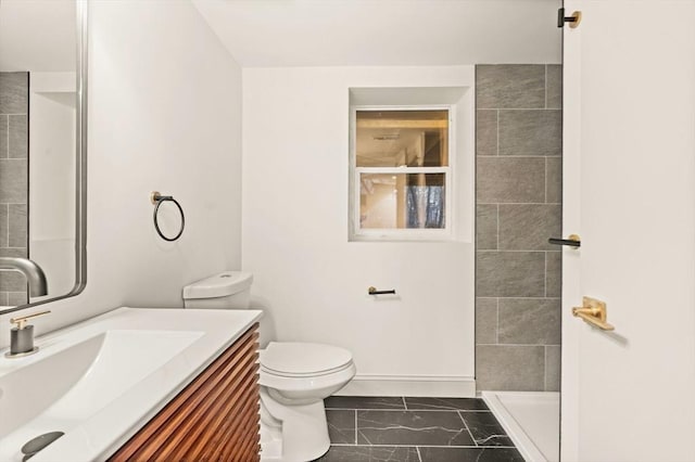 bathroom featuring toilet, a shower, and vanity