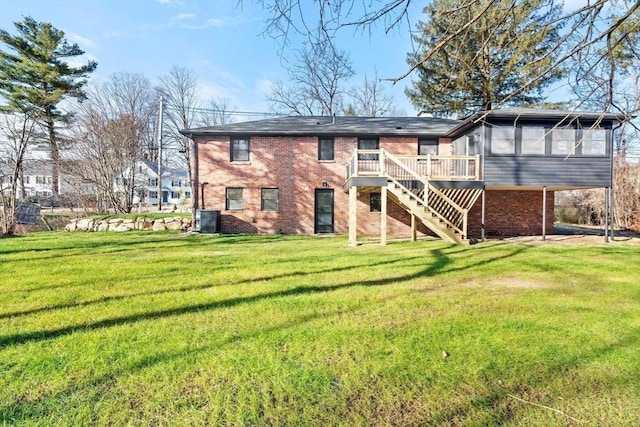 rear view of property with a wooden deck, a sunroom, a lawn, and central air condition unit