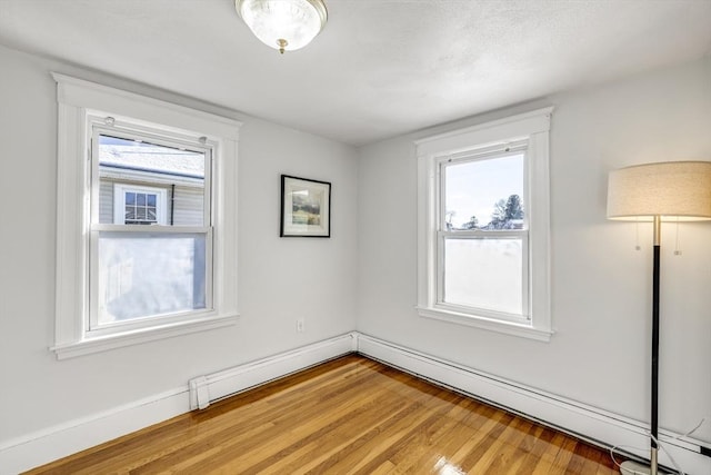 unfurnished room with wood-type flooring and a baseboard radiator