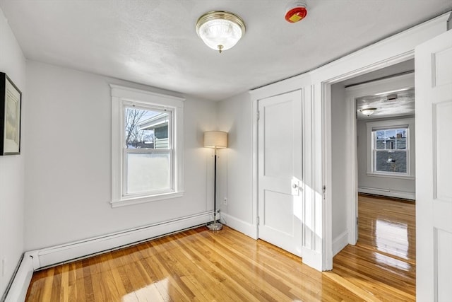 spare room featuring hardwood / wood-style flooring, a baseboard radiator, and plenty of natural light