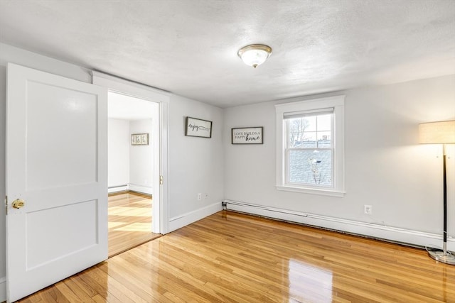 empty room with a baseboard radiator, hardwood / wood-style floors, and a textured ceiling