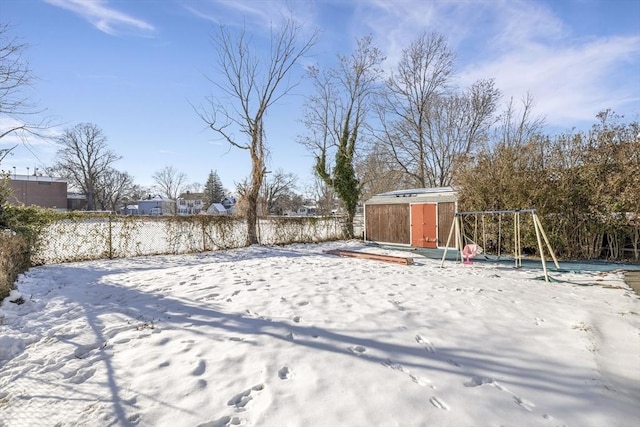 snowy yard with a storage unit and a playground