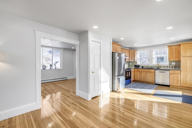 kitchen featuring sink, light wood-type flooring, appliances with stainless steel finishes, decorative backsplash, and a baseboard heating unit