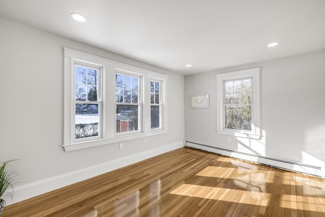 unfurnished room featuring a baseboard heating unit and hardwood / wood-style floors