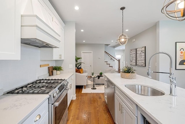 225 Amory St, Boston, MA 02130 - kitchen featuring stainless steel appliances, a sink, wood finished floors, white cabinets, and premium range hood