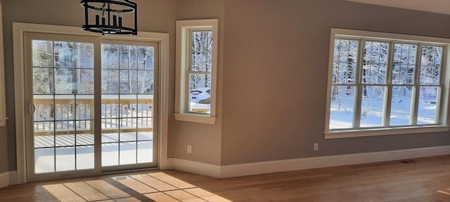 doorway featuring hardwood / wood-style floors, an inviting chandelier, and a healthy amount of sunlight