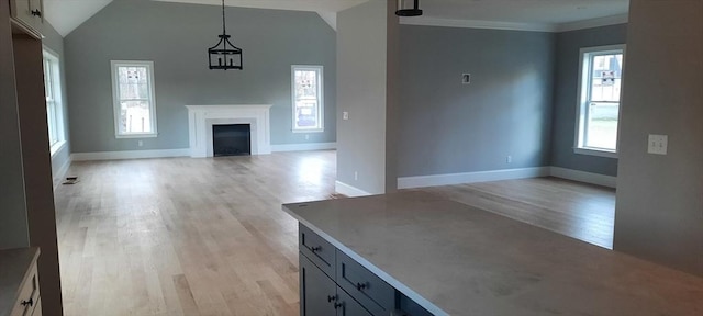 unfurnished living room with vaulted ceiling, crown molding, and light hardwood / wood-style flooring