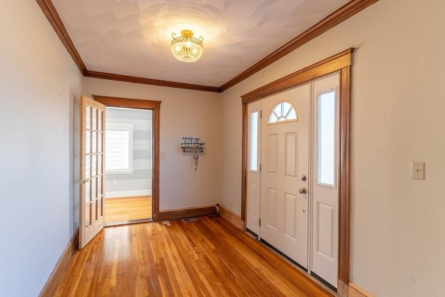 entryway featuring plenty of natural light, ornamental molding, and light wood-type flooring