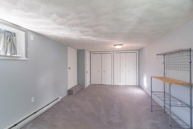 interior space featuring a baseboard radiator, carpet floors, two closets, and a textured ceiling