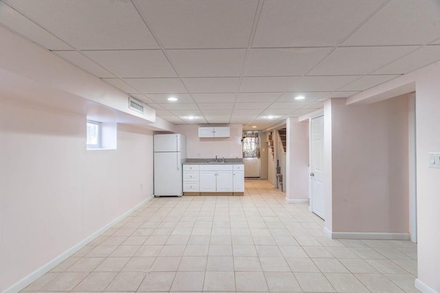 kitchen with white fridge, sink, a paneled ceiling, and white cabinets