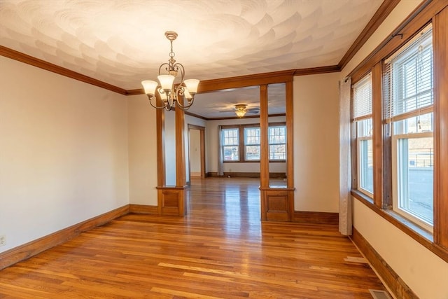 spare room featuring crown molding, light hardwood / wood-style floors, and a chandelier