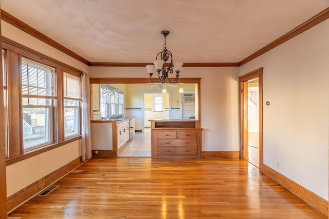 unfurnished dining area featuring crown molding, a chandelier, and light hardwood / wood-style floors