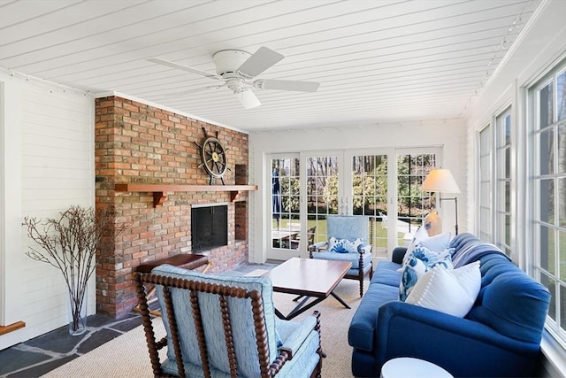 sunroom / solarium with a fireplace, french doors, and ceiling fan