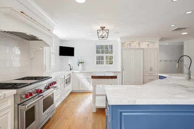 kitchen with appliances with stainless steel finishes, blue cabinets, sink, white cabinets, and custom exhaust hood