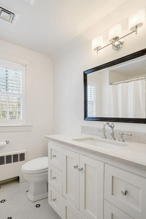 bathroom with vanity, toilet, radiator, and tile patterned flooring