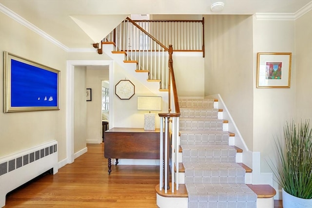 staircase featuring ornamental molding, radiator, and hardwood / wood-style floors