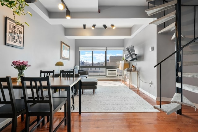 dining space featuring a tray ceiling, a wall unit AC, and hardwood / wood-style flooring