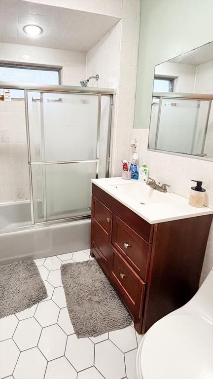 full bathroom with bath / shower combo with glass door, toilet, tile patterned flooring, and vanity