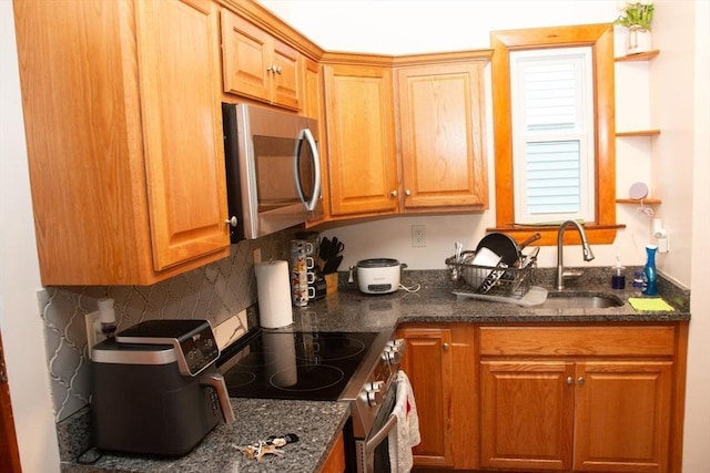 kitchen featuring a sink, dark stone countertops, and stainless steel appliances