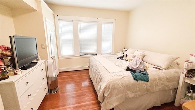 bedroom featuring baseboard heating, wood finished floors, and baseboards