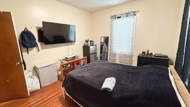 bedroom featuring wood finished floors and freestanding refrigerator
