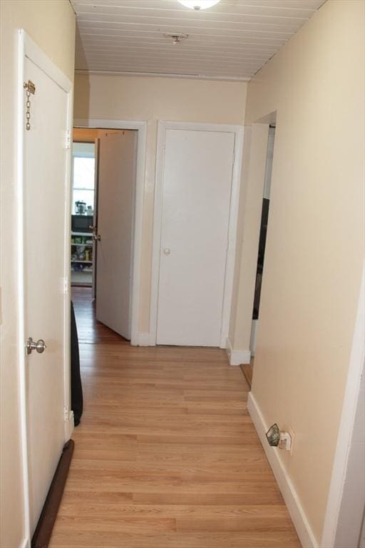 hall with baseboards and light wood finished floors