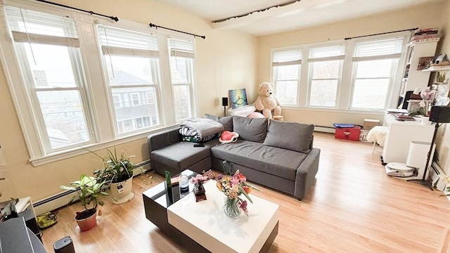 living area with a baseboard heating unit, beamed ceiling, wood finished floors, and plenty of natural light