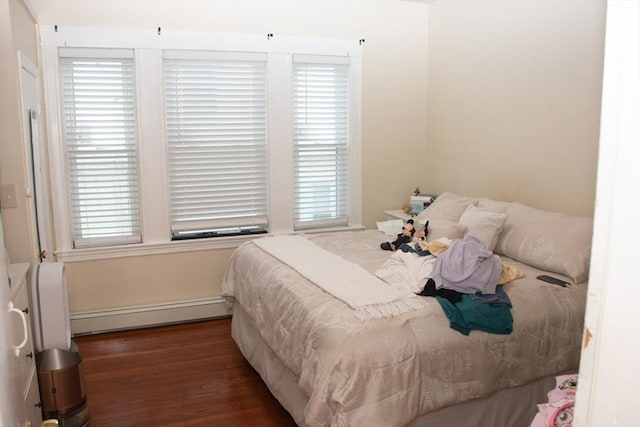 bedroom with wood finished floors, baseboard heating, and multiple windows