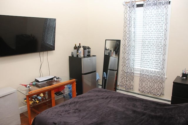 bedroom featuring multiple windows, freestanding refrigerator, and a baseboard radiator